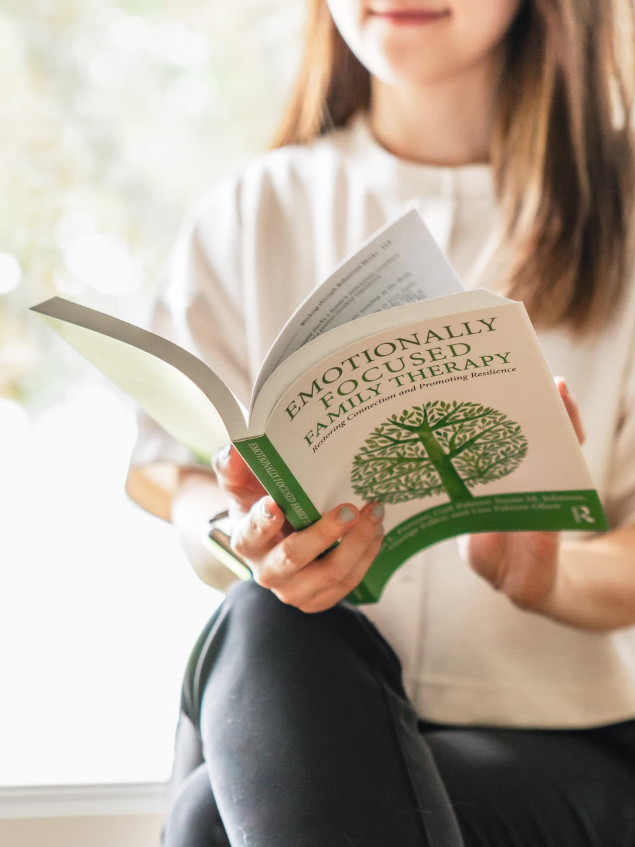 Kathy reading a book called Emotionally Focused Family Therapy