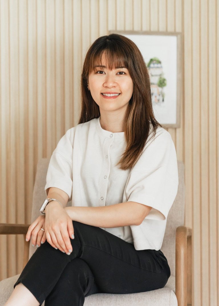 Kathy sitting on an arm chair smiling